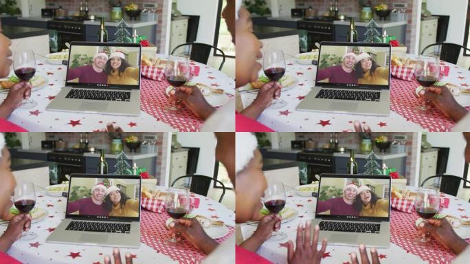 非裔美国人夫妇与葡萄酒使用笔记本电脑进行圣诞节视频通话与夫妇在屏幕上