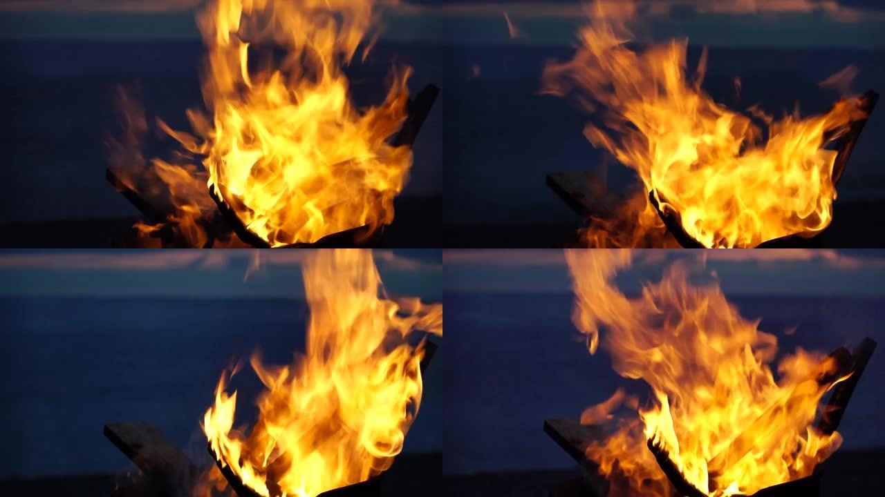 火盆烧烤烧烤炉中鲜红色的大火特写镜头。明亮的篝火，充满活力的灯光，灰烬，烟雾，并在日落之后平静的大海