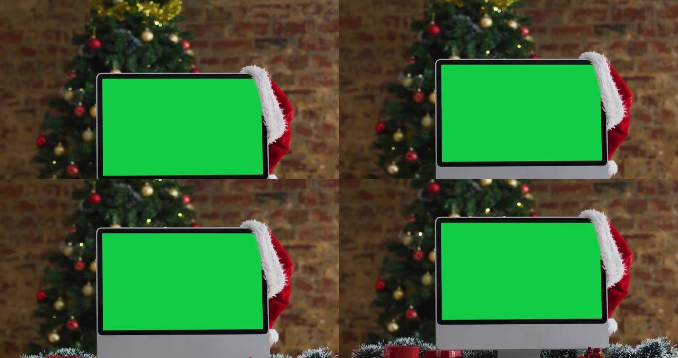 圣诞老人帽子挂在电脑显示器上，有复印空间，有圣诞装饰品和树
