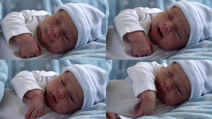 初生婴儿脸部肖像早期在宏观上醒来，睁开眼睛在蓝星背景上。孩子在帽子上生命的开始。婴儿，分娩，出生的最