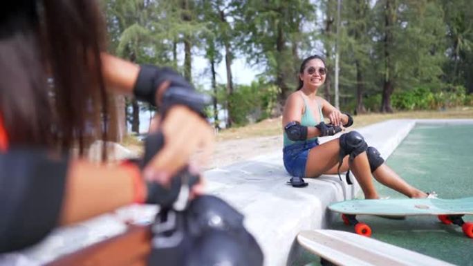 亚洲女子和女朋友在滑板公园滑板前戴安全滑板护膝