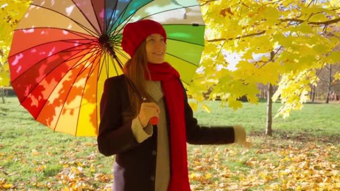 美丽的幸福女人站在公园里撑着伞，微笑着。阳光明媚