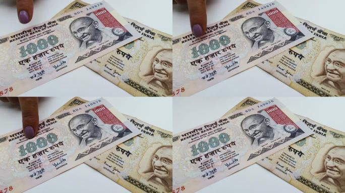 旧印度卢比钞票。手指指着纸条。