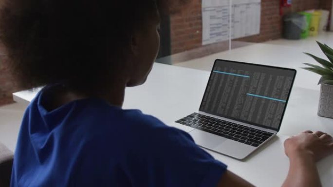 坐在办公桌前的非洲裔美国妇女在笔记本电脑屏幕上观看编码数据处理