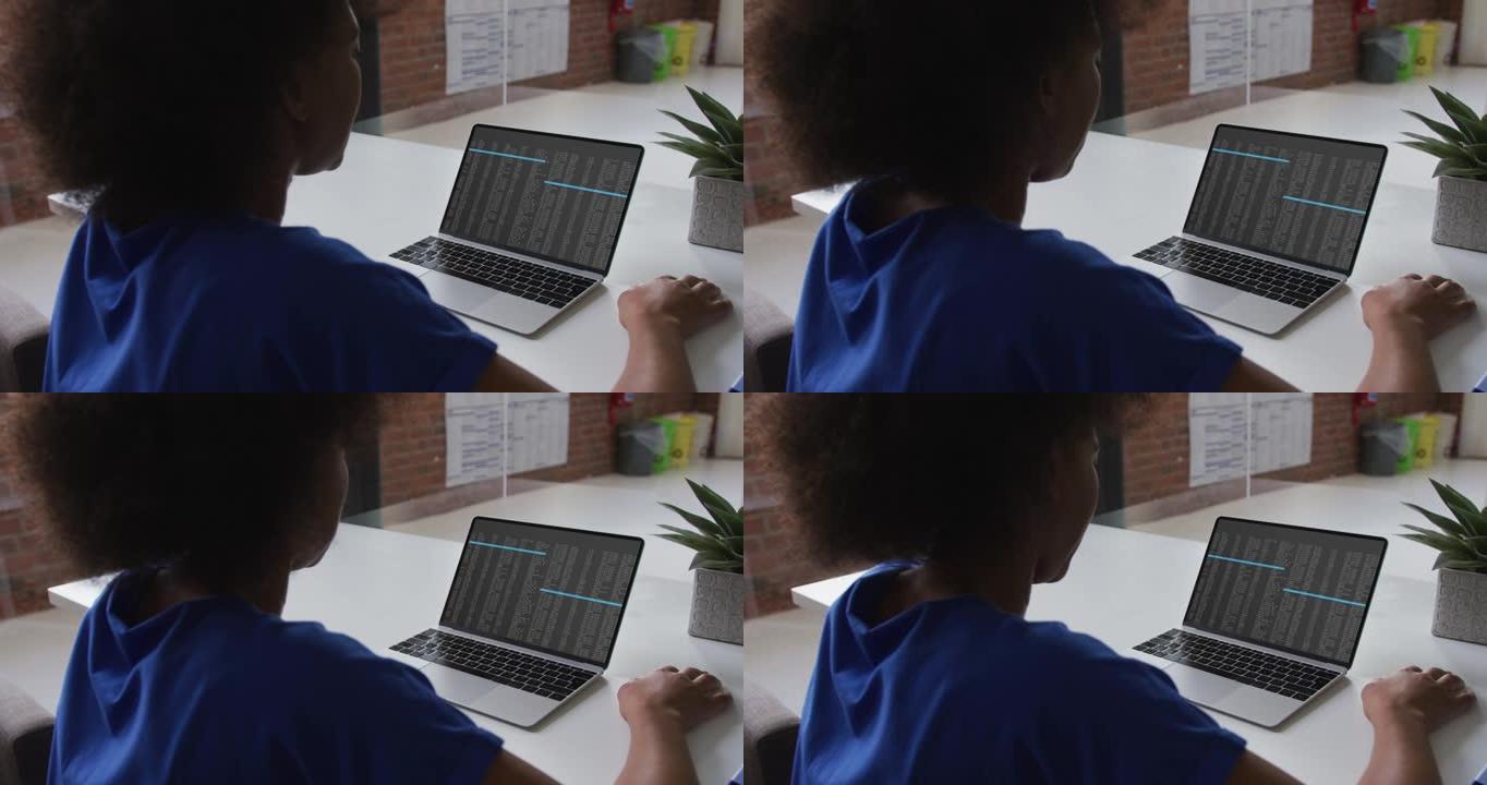 坐在办公桌前的非洲裔美国妇女在笔记本电脑屏幕上观看编码数据处理