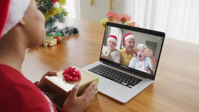戴着圣诞老人帽子的非洲裔美国妇女使用笔记本电脑进行圣诞节视频通话，屏幕上有家人