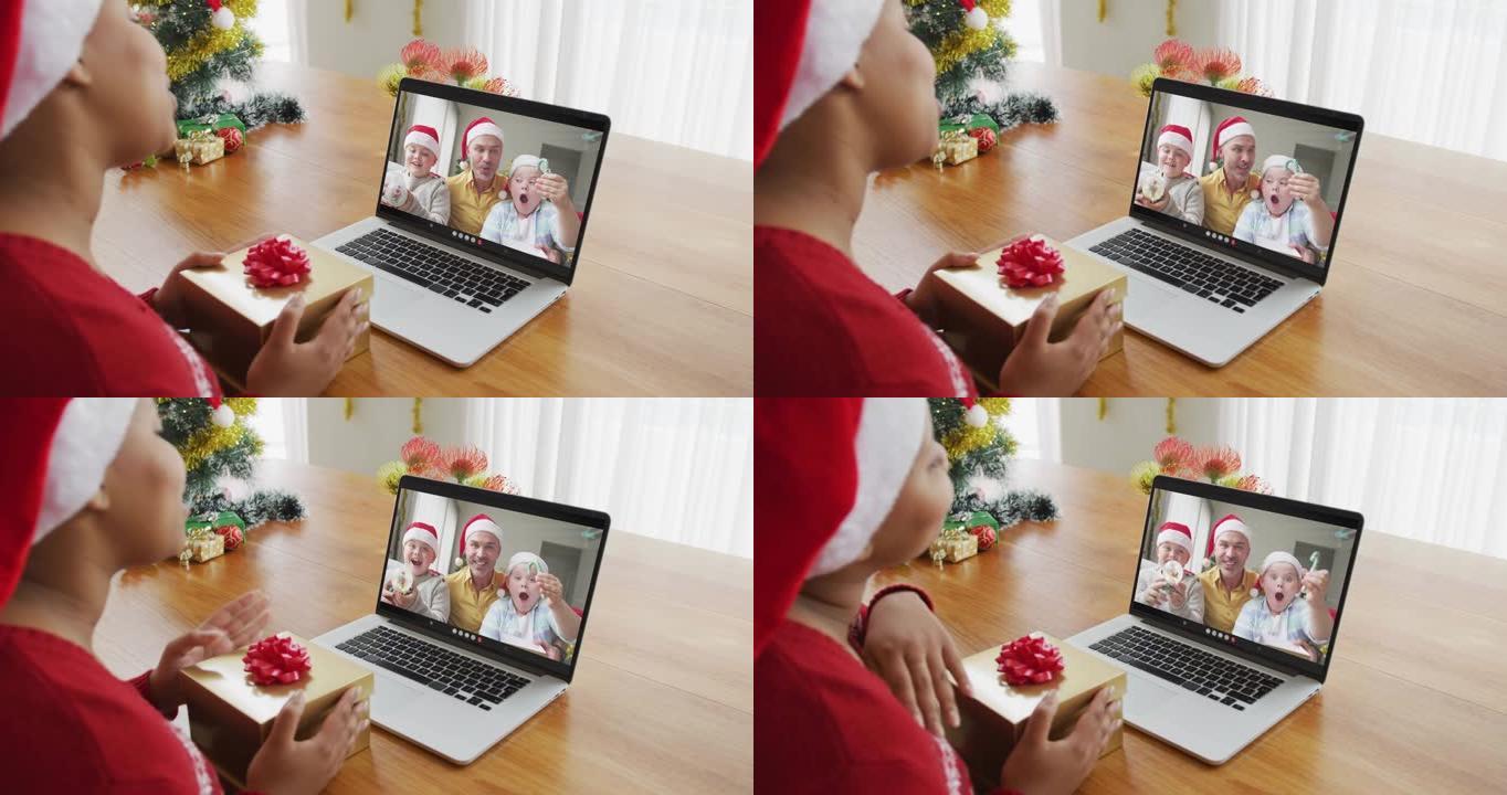 戴着圣诞老人帽子的非洲裔美国妇女使用笔记本电脑进行圣诞节视频通话，屏幕上有家人