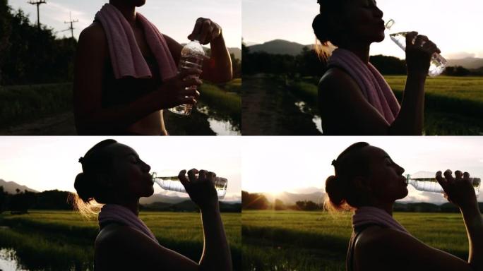 在日落时分，亚洲妇女在玉米田旁阳光直射后跑到外面喝淡水的剪影。