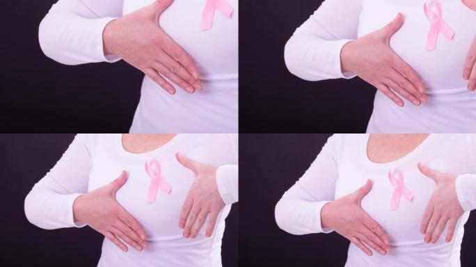白种人妇女穿粉红色的癌症意识丝带，黑色背景的中段视频