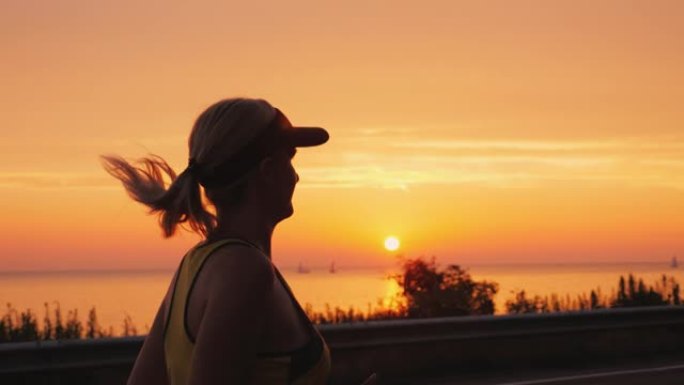 运动的年轻女子在太阳落山的海边慢跑。Steadicam射击