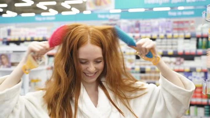 快乐的红发女性在商店里选择新梳子