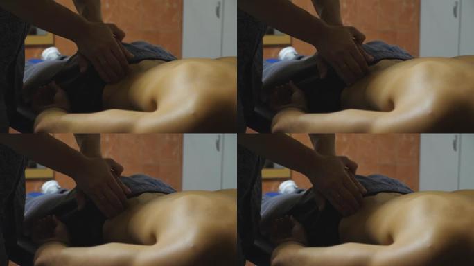 男按摩师的手在客厅按摩年轻运动员的腰。专业按摩师在艰苦训练后放松和振兴运动员的肌肉。健康生活方式的概