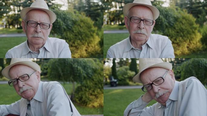 戴着帽子戴眼镜的体贴老人的肖像悲伤地看着相机