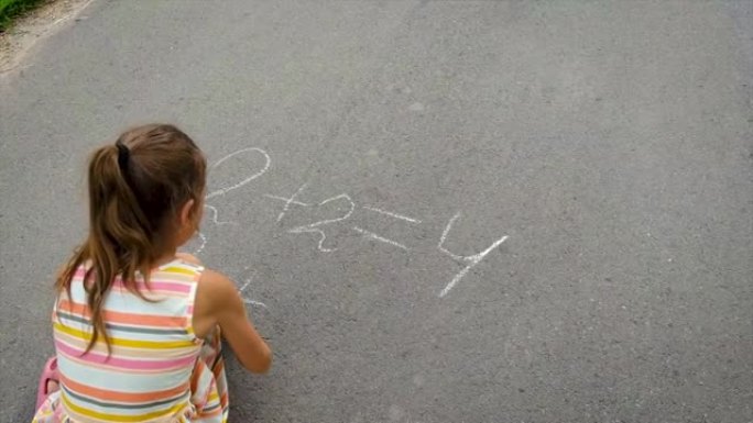 孩子在沥青上写方程式。选择性聚焦。