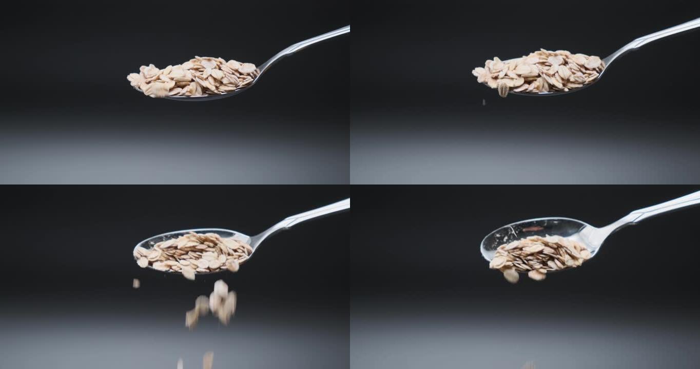 燕麦慢动作从勺子上掉下来。干燕麦薄片颗粒