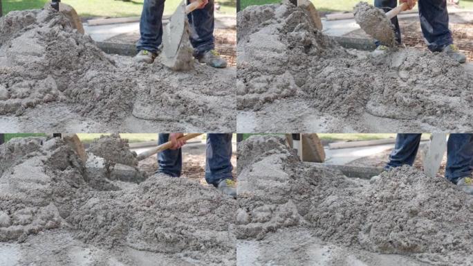 穿着脏衣服的工人使用金属铲子搅拌湿混凝土，建筑商为施工现场的不同工程准备砂浆。用铲子搅拌水泥和水的过