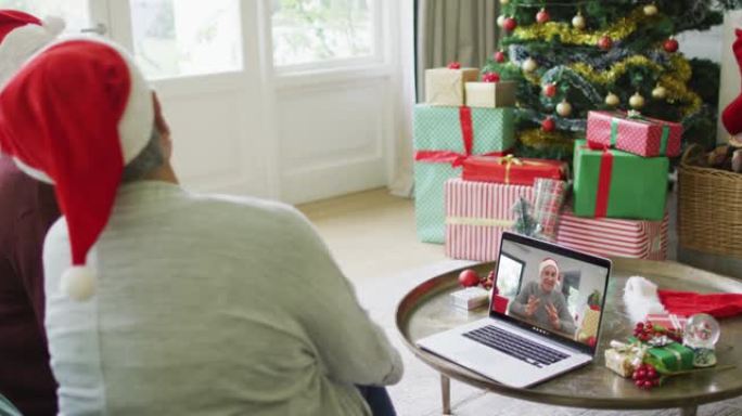 两名资深女性朋友使用笔记本电脑与屏幕上的男人进行圣诞节视频通话
