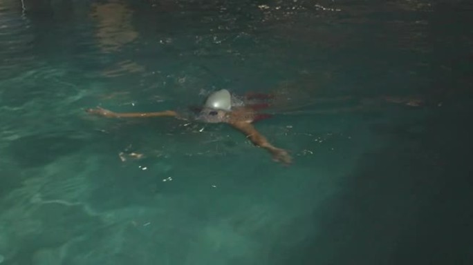 戴着泳帽和护目镜的年轻女子在酒店游泳池享受
