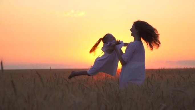 妈妈和女儿在野外玩得很开心。日落时分，妈妈和女儿快乐。两个女孩姐妹正在麦田里散步。自然界中的人。自由