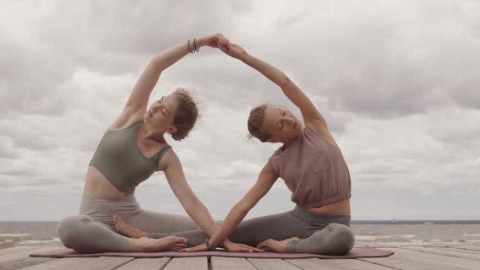 女性朋友在户外练习双人瑜伽