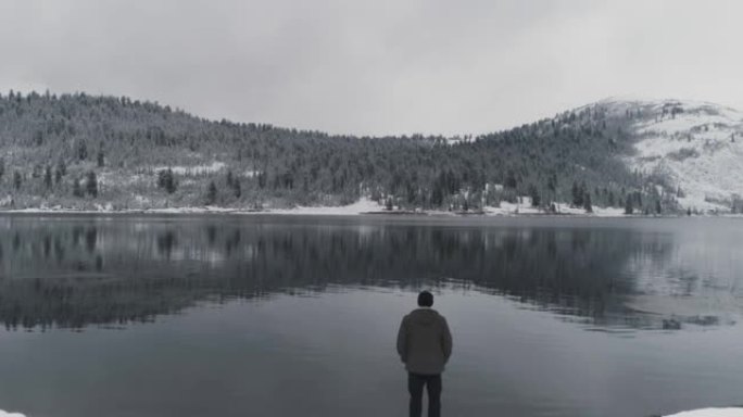 冬天，男人背站在山上的湖岸上