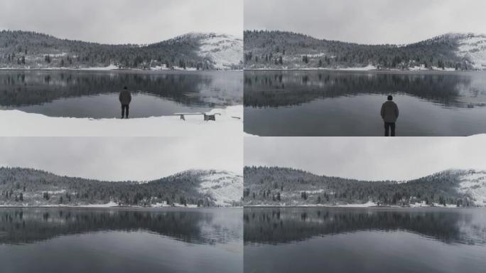 冬天，男人背站在山上的湖岸上
