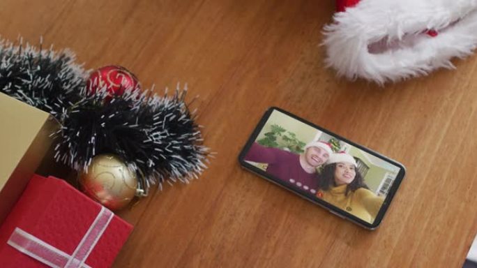 在智能手机上的圣诞节视频通话中戴着圣诞老人帽子的微笑夫妇