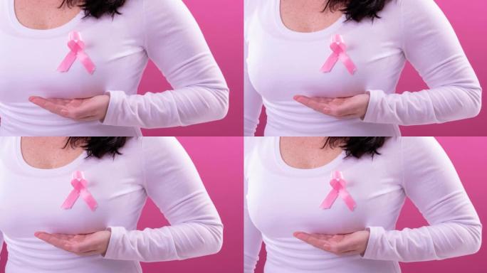 视频上腹部的白人妇女穿着粉红色的癌症意识丝带，粉红色的背景