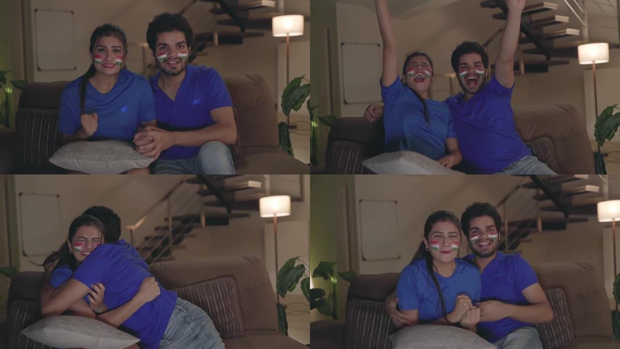 年轻的印度夫妇在电视机上观看、欢呼和享受板球比赛。