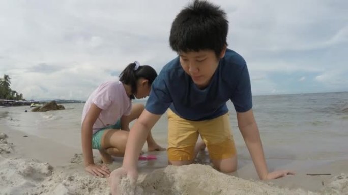 快乐的亚洲儿童在度假时与家人一起在沙滩上玩沙子，生活方式理念。