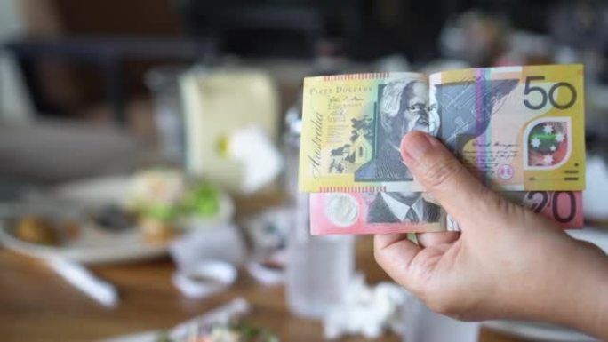 女人的手拿着澳大利亚钞票在餐厅付款。