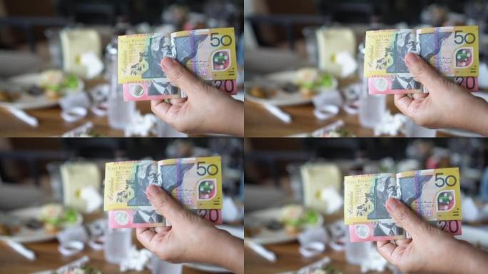 女人的手拿着澳大利亚钞票在餐厅付款。