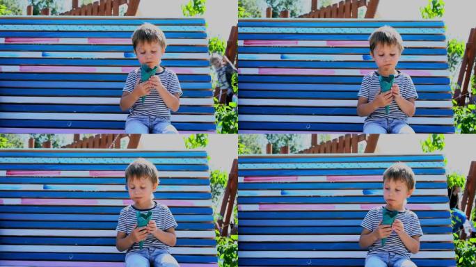 可爱的高加索男孩坐在公园的长凳上吃冰激丸