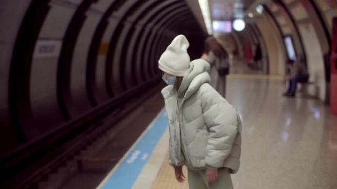 戴口罩的女孩在地铁里等火车