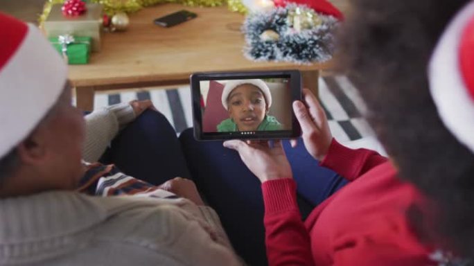 非裔美国母亲和女儿使用平板电脑与屏幕上的男孩进行圣诞节视频通话