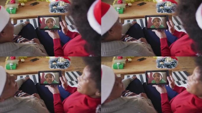 非裔美国母亲和女儿使用平板电脑与屏幕上的男孩进行圣诞节视频通话
