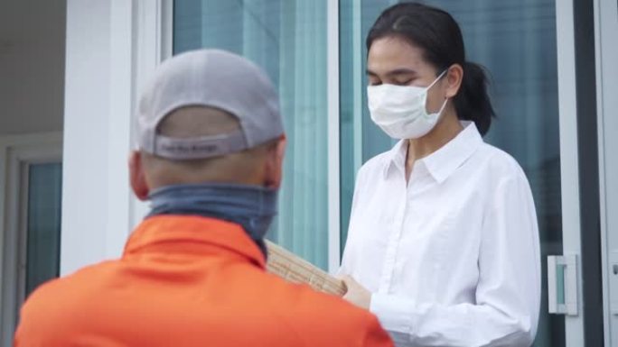 从送货员那里拿包裹的女人。