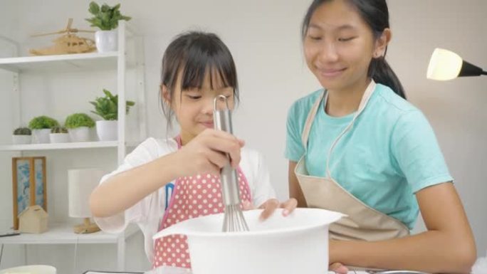 快乐的亚洲孩子在家里学习做饼干，女孩在搅拌碗里搅拌面粉。