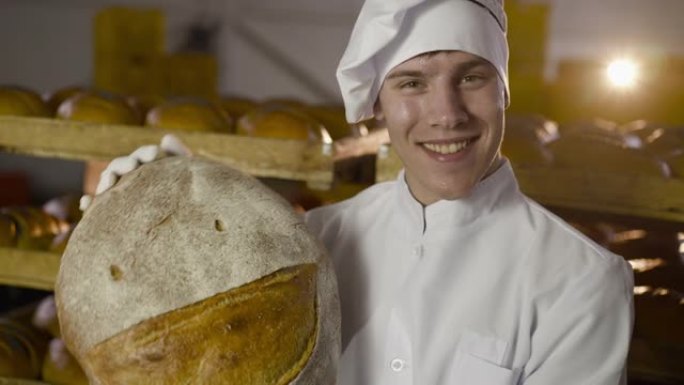 快乐的面包师欢欣鼓舞，露出带着微笑的大圆面包