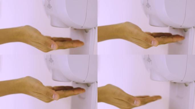 近距离4K的亚洲妇女正在使用自动酒精凝胶机，将手放在机器下面。是医院为杀灭病毒而生产的卫生保健用品。