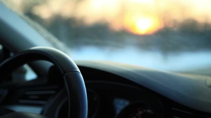 冬季驾驶汽车时，驾驶员的手握住方向盘，特写。在积雪湿滑的道路上驾驶理念，霜冻
