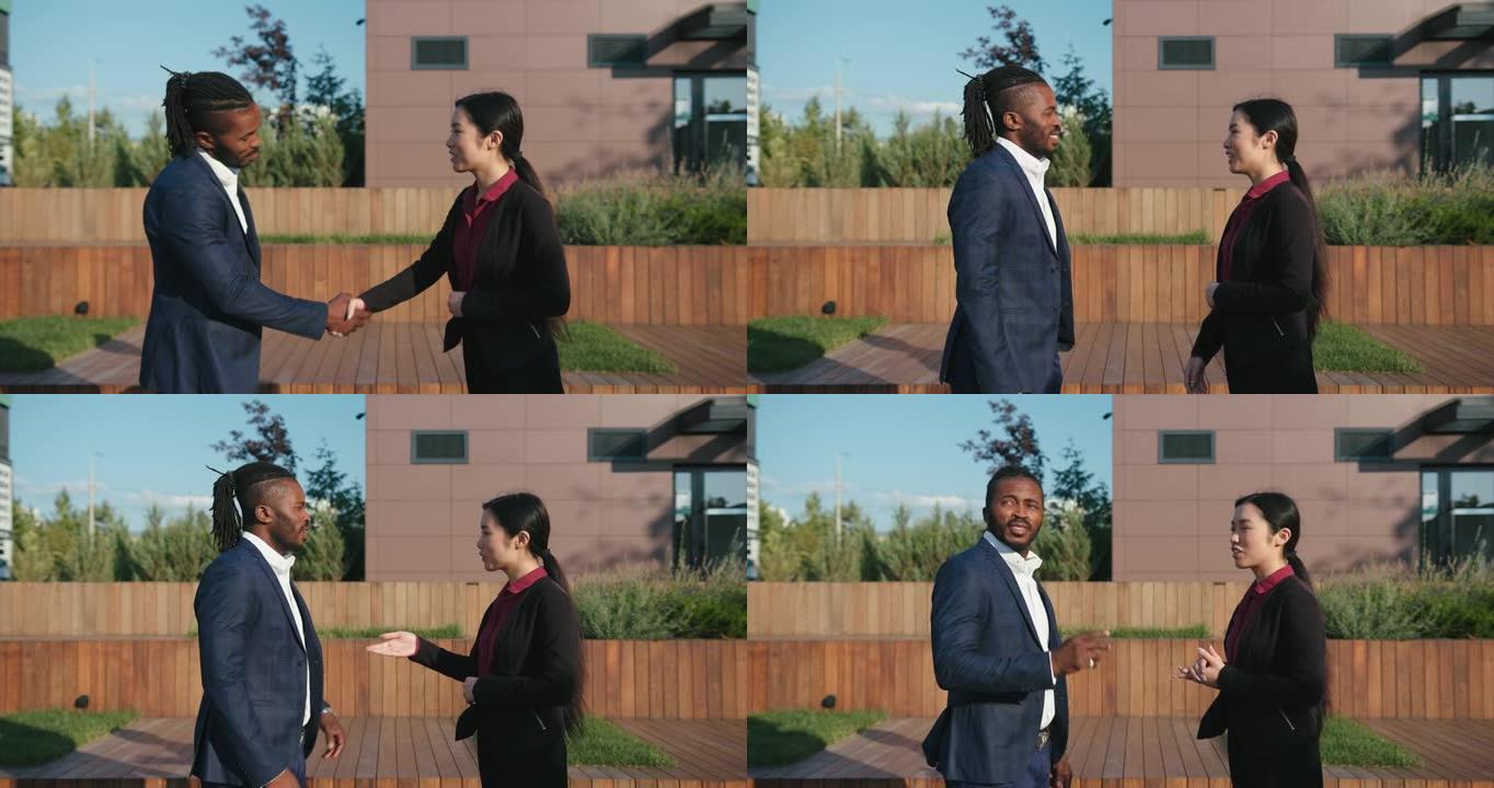 亚洲妇女与黑人男子握手反对办公楼