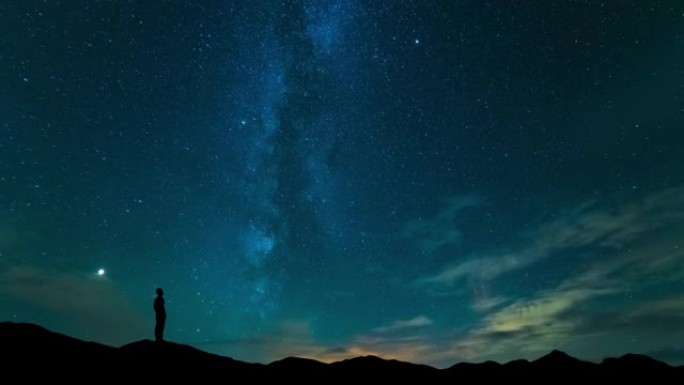 该名男子站在星空背景下的山顶上。时间流逝