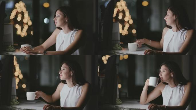 4k视频片段，一名年轻的女商人晚上在办公室工作时喝杯咖啡