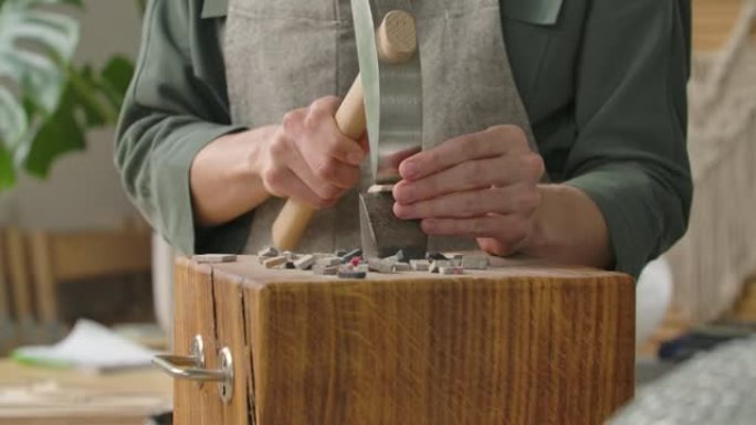 男性的手使用特殊的锤子将马赛克瓷砖分成两半。镶嵌图案石材的制备。在创意车间手工制作。特写。慢动作