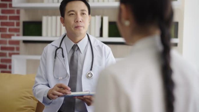 一位亚洲男性整形外科医生的肖像与一位女性患者交谈，在诊所办公室咨询医学和保健概念。