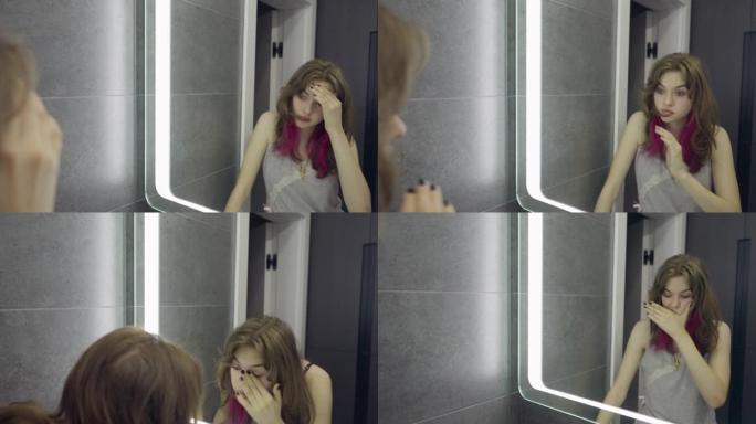 昏昏欲睡的年轻女子看着镜子里的自己
