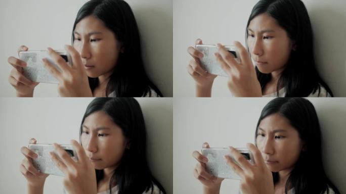亚洲女孩在家坐在床上玩手机游戏，生活方式概念。