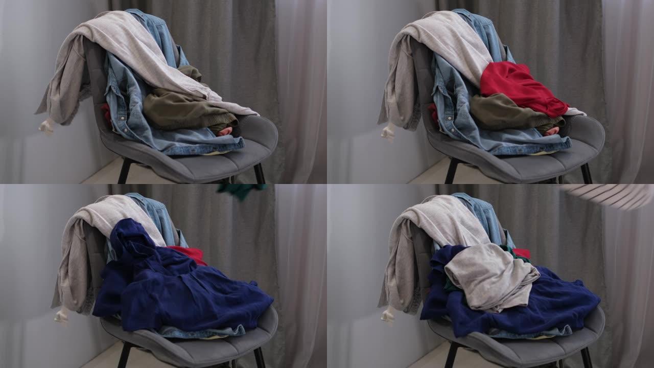 人把用过的衣服扔在椅子上。把衣服堆在椅子上。一堆旧衣服用于捐赠和回收。极简主义、混乱和衣柜清洁的概念