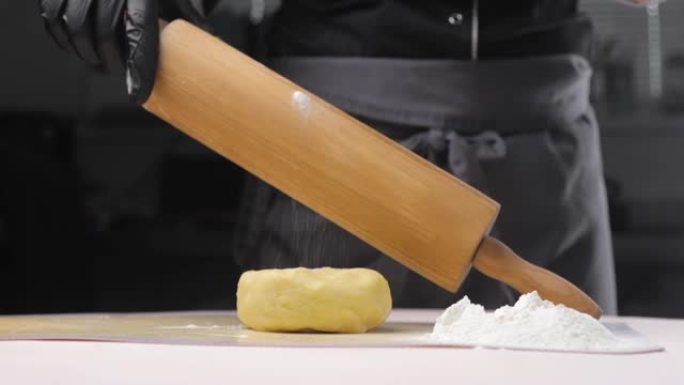 面包师或厨师将要把面团在白色的桌子上滚动，用面粉撒上，这样它就不会在滚动时粘在木制的rolling面